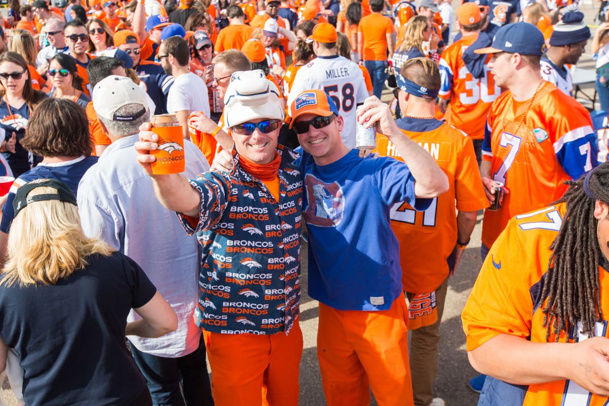 Two fans in Broncos gear toasting in the crowd