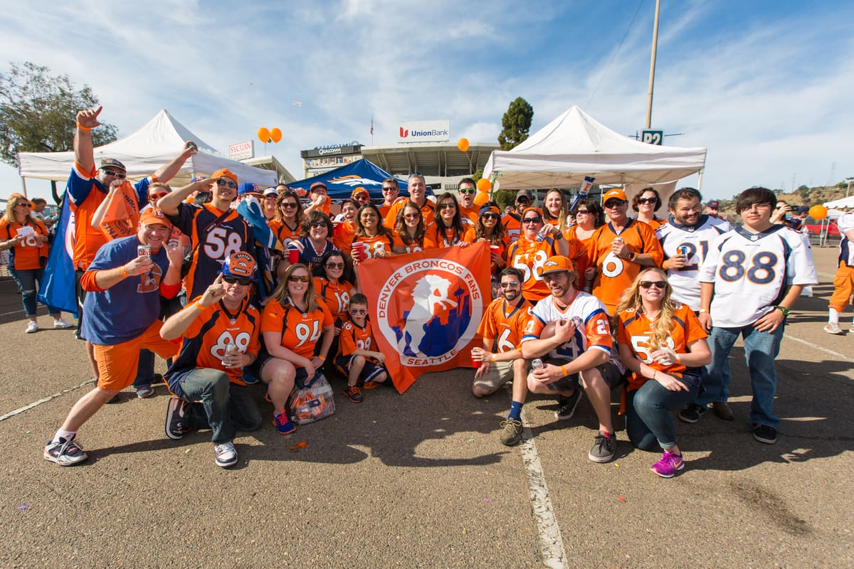 Fans posing with a visiting Broncos fan club banner
